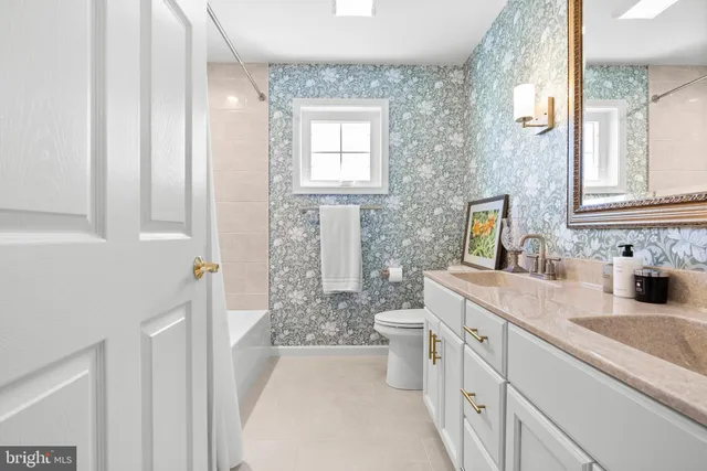 a bathroom with double vanity sink a mirror a toilet and a shower