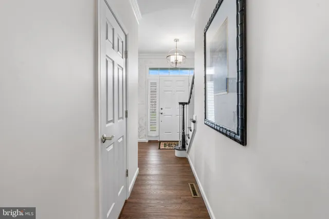 a view of a hallway with wooden floor and a bathroom