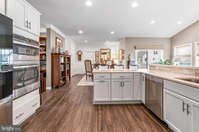 a kitchen with stainless steel appliances granite countertop a refrigerator oven a sink dishwasher and white cabinets with wooden floor