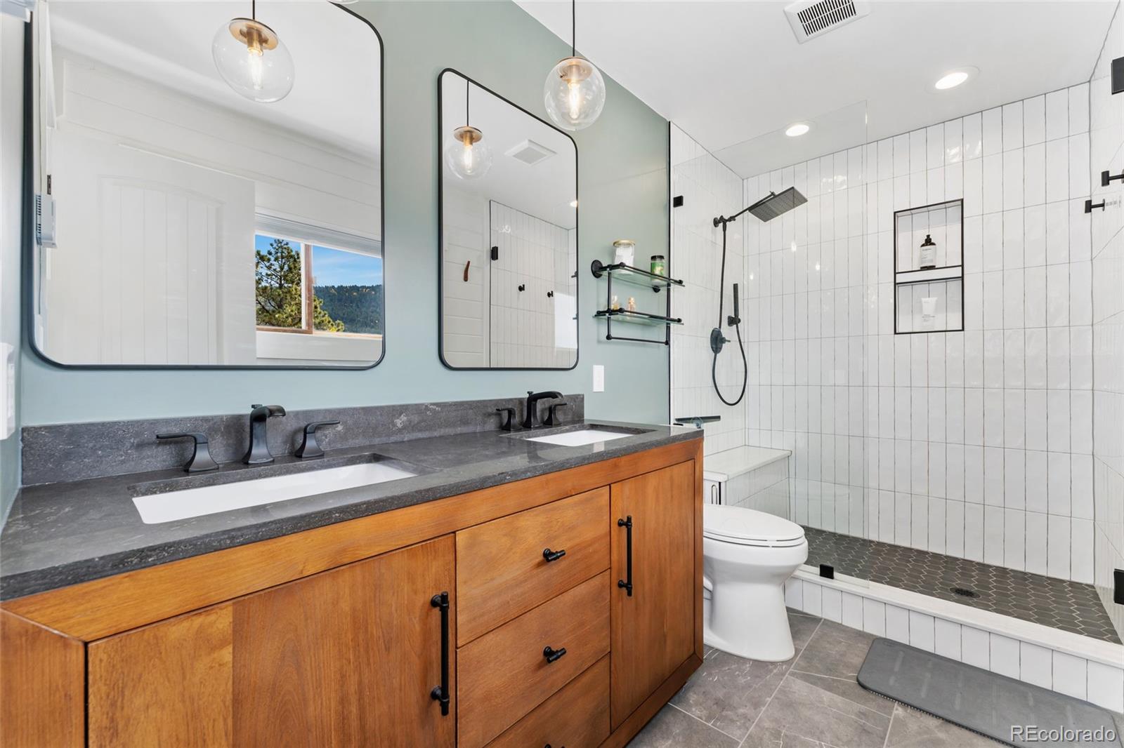 24333 Bent Feather Road Conifer, CO 80433 - Photo 21 of 50 a bathroom with a double vanity sink toilet mirror and shower