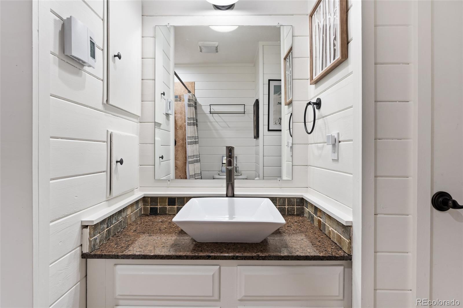 24333 Bent Feather Road Conifer, CO 80433 - Photo 24 of 50 a bathroom with a granite countertop sink a mirror and shower