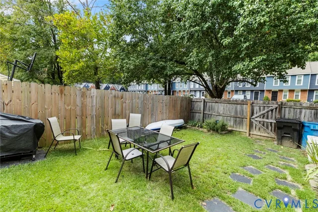 a view of a backyard with table and chairs and a barbeque with wooden fence