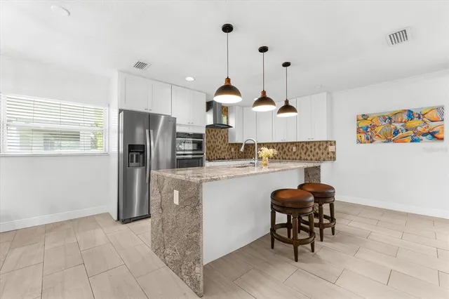 a kitchen with stainless steel appliances granite countertop a refrigerator a sink a stove and a wooden floors