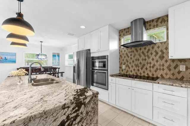 a kitchen with stainless steel appliances kitchen island granite countertop a refrigerator and a sink