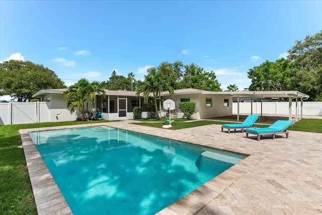 a view of backyard with swimming pool and seating space