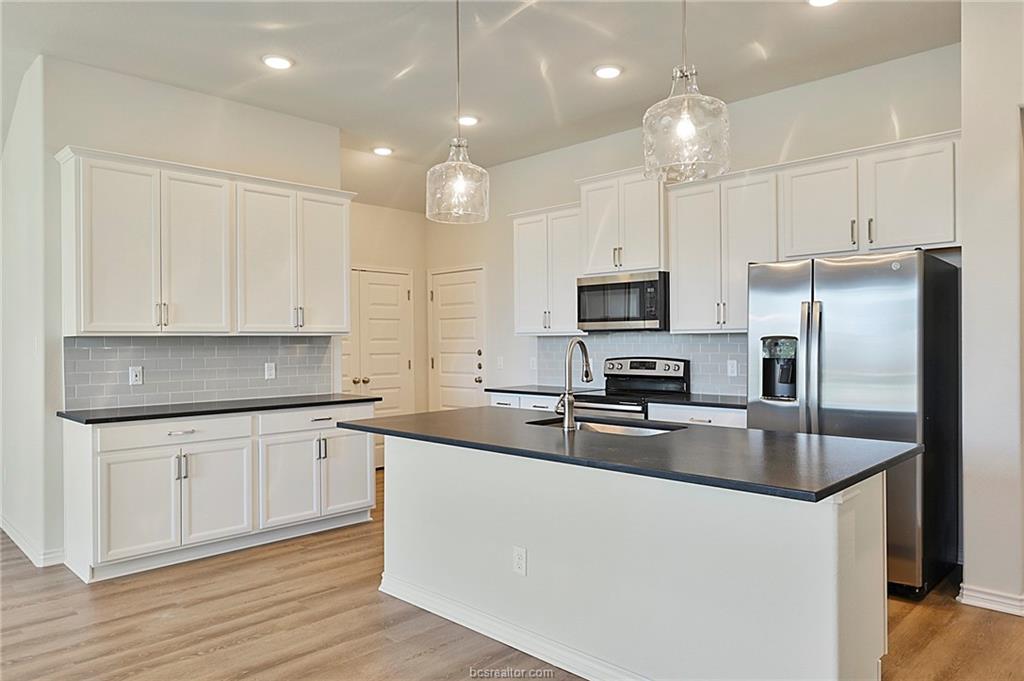 3124 Tarleton Court Bryan, TX 77808 - Photo 7 of 22 a kitchen with stainless steel appliances granite countertop a refrigerator a sink dishwasher a stove top oven a refrigerator with white cabinets and wooden floor