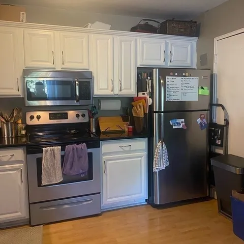 a kitchen with granite countertop white cabinets and refrigerator