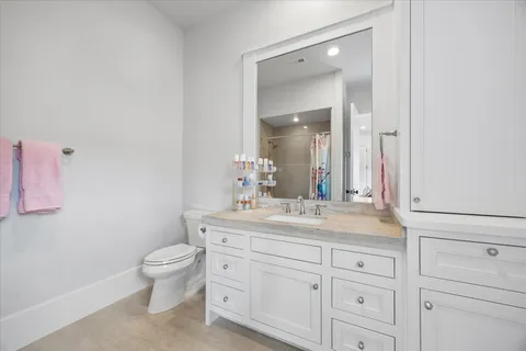 a bathroom with a granite countertop sink a toilet and a mirror