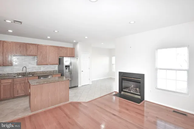 a kitchen with granite countertop a stove top oven a sink dishwasher and a refrigerator with wooden floor