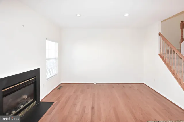 a view of an empty room with wooden floor and a fireplace
