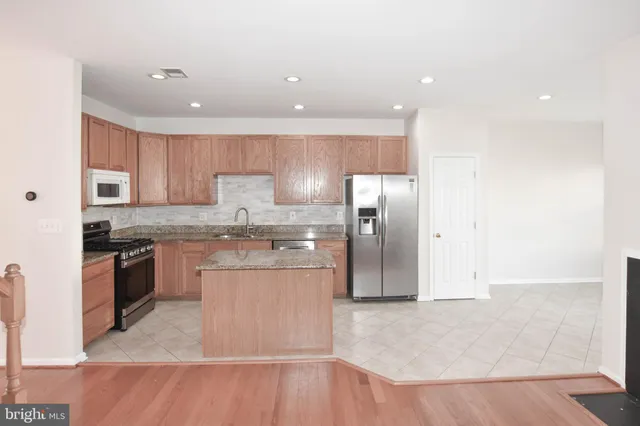 a kitchen with stainless steel appliances granite countertop a refrigerator a sink a stove and oven