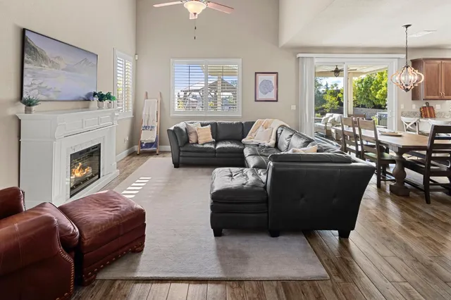 a kitchen with stainless steel appliances granite countertop a refrigerator a stove a sink a dining table and chairs with wooden floor