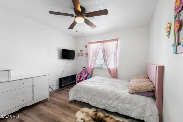 a bedroom with a bed and a flat tv screen on dresser