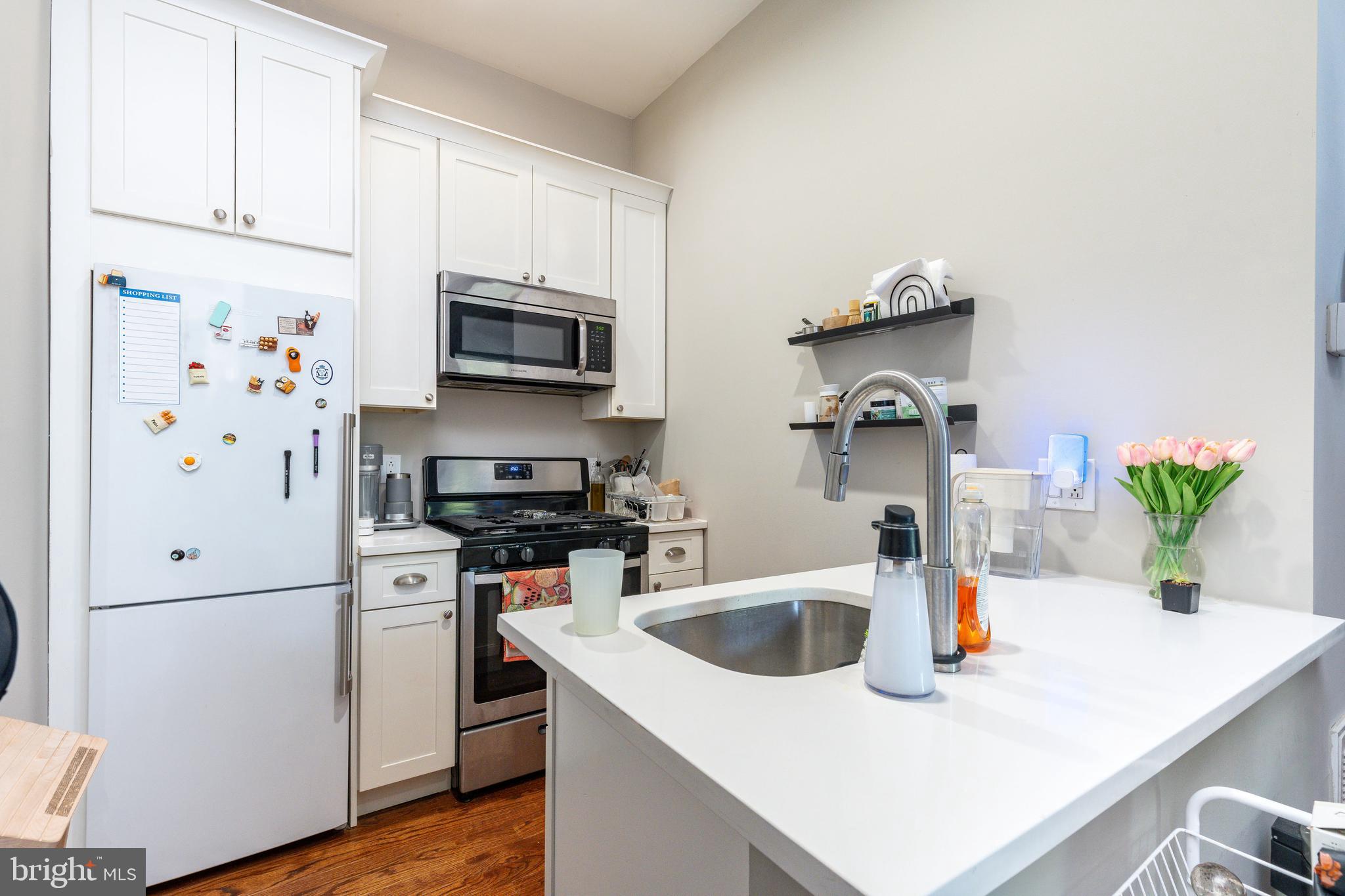 109-15 Carpenter Lane Philadelphia, PA 19119 - Photo 32 of 47 a kitchen with stainless steel appliances a stove a sink a refrigerator a microwave and cabinets