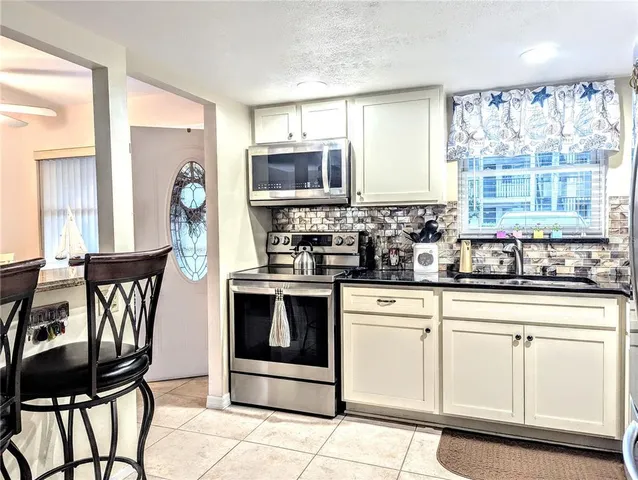 a kitchen with stainless steel appliances granite countertop a stove a sink and white cabinets