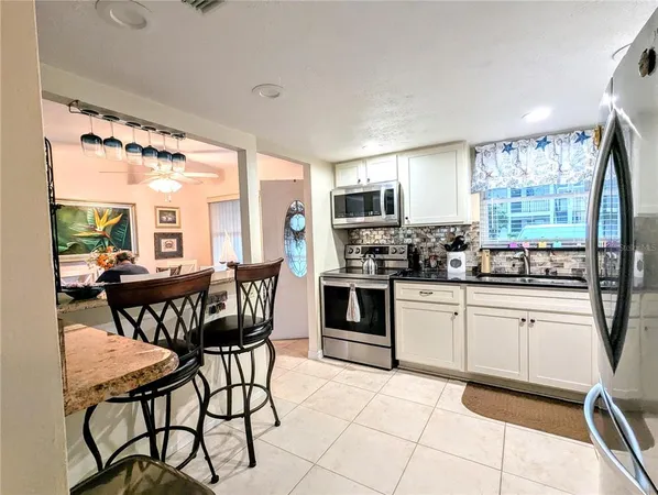 a kitchen with stainless steel appliances granite countertop a stove a sink dishwasher a dining table and chairs with wooden floor