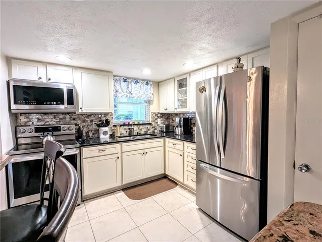 a kitchen with stainless steel appliances granite countertop a refrigerator sink and microwave