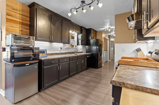 a kitchen with stainless steel appliances granite countertop wooden cabinets a sink dishwasher a stove and a refrigerator