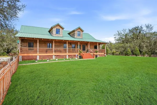 a view of a big house with a big yard and large trees