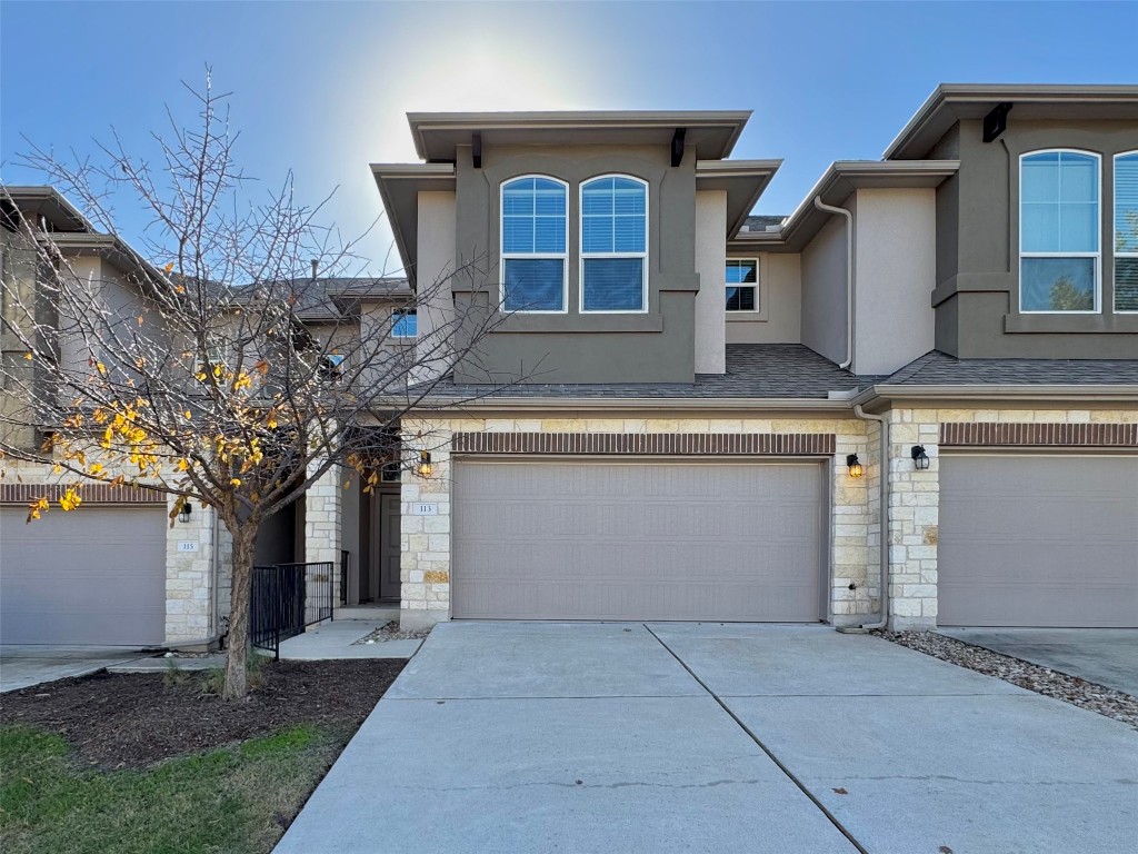 View of front of property with stone siding, stucco siding, driveway, and an attached garage