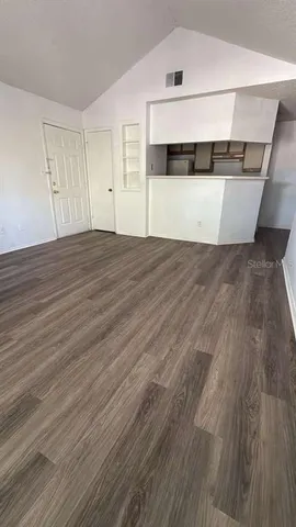 a view of an empty room with wooden floor and cabinet