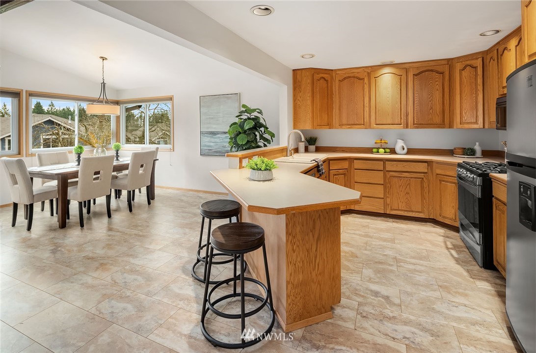 6611 Southeast 5th Place Renton, WA 98059 - Photo 4 of 25 a kitchen with stainless steel appliances granite countertop a stove top oven a sink a dining table and chairs with wooden floor