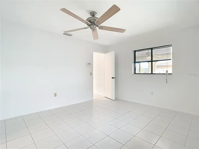 an empty room with windows and fan