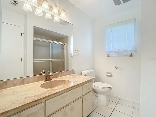 a bathroom with a granite countertop sink a toilet and a mirror