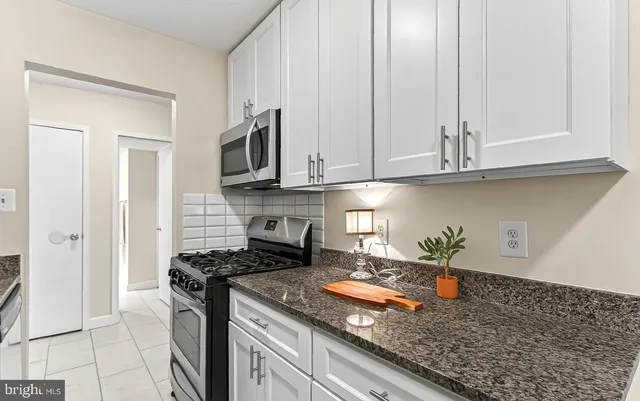 a kitchen with granite countertop stainless steel appliances a stove a microwave and cabinets