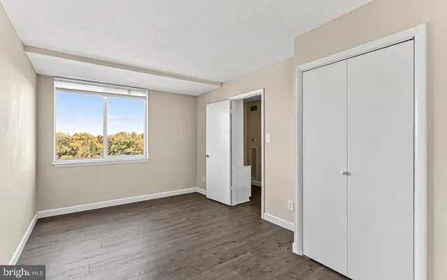 an empty room with wooden floor closet and windows