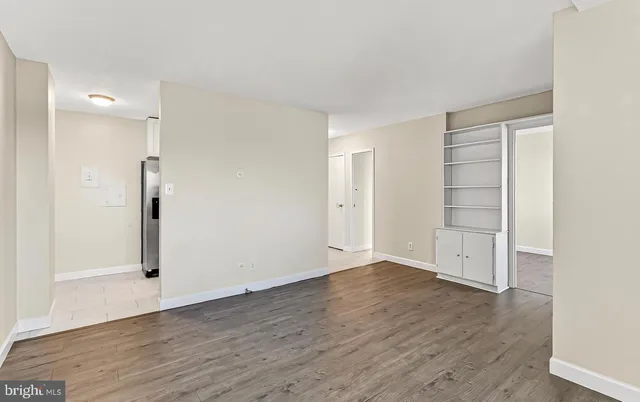 an empty room with wooden floor & closet area
