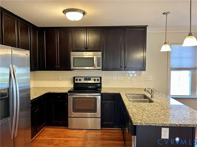 a kitchen with kitchen island granite countertop stainless steel appliances and wooden cabinets