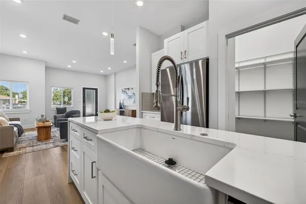 a large kitchen with a large counter top space a sink stainless steel appliances and cabinets