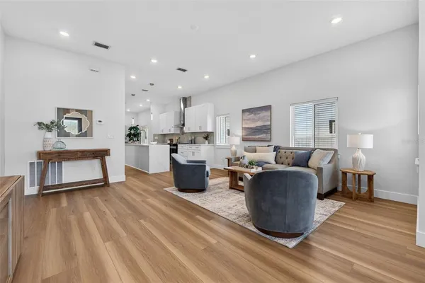 a living room with furniture a wooden floor and kitchen view