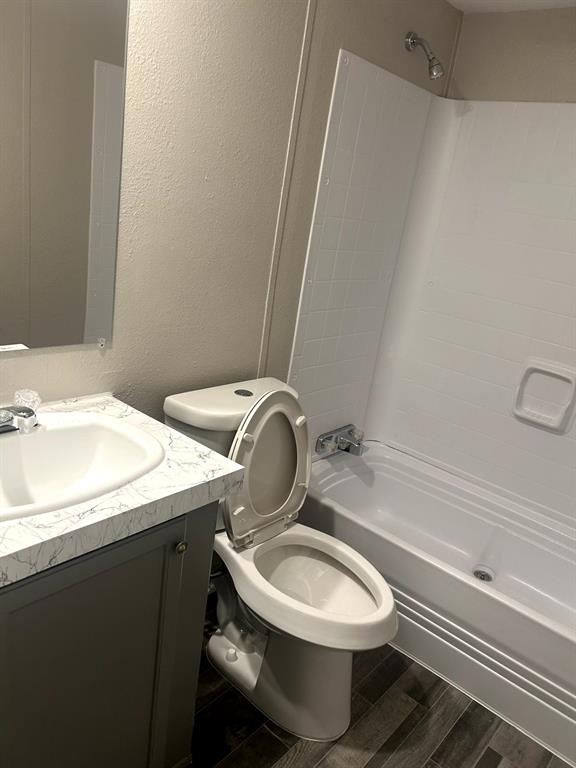 717 Byron Road Wilmer, TX 75172 - Photo 20 of 20 Bathroom featuring a bathtub/shower combination with white surround, a toilet, and a vanity with a white basin and a stone-look countertop