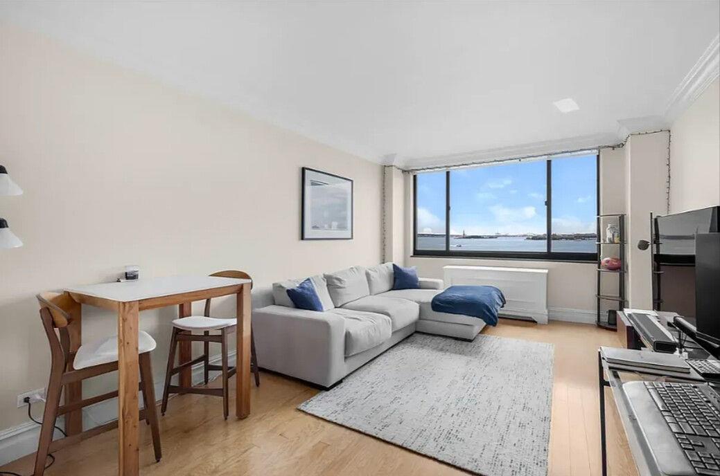 204 Rector Place, Unit 10L Manhattan, NY 10280 - Photo 1 of 10 a living room with furniture and a flat screen tv
