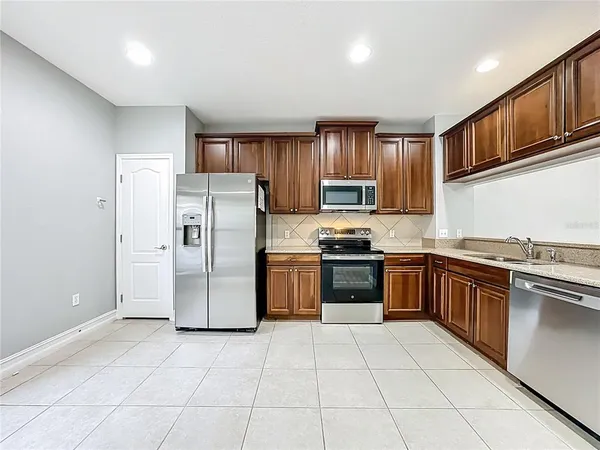 a kitchen with granite countertop a refrigerator stove top oven and sink