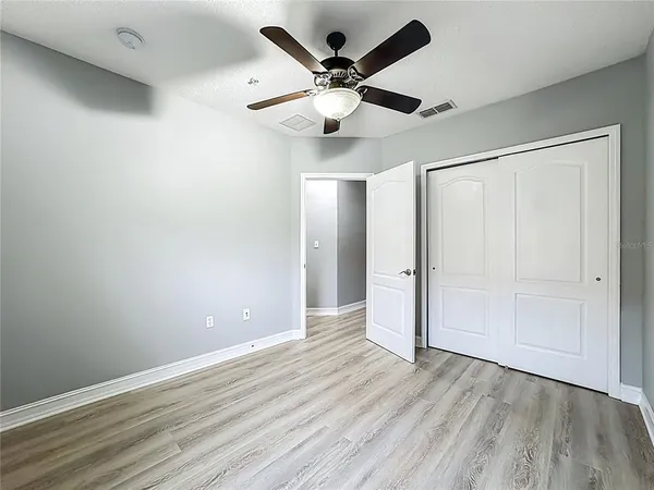 an empty room with wooden floor and ceiling fan