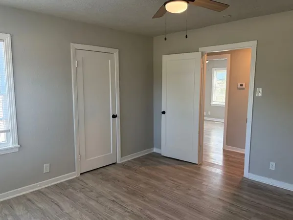a view of an empty room with wooden floor and window