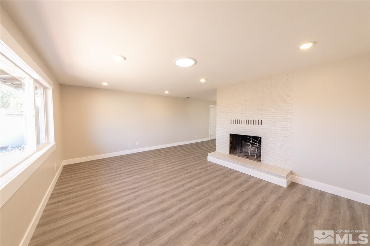 1070 Foothill Road Reno, NV 89511 - Photo 3 of 17 an empty room with wooden floor fireplace and windows