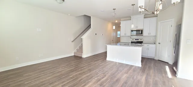 a kitchen with kitchen island a white counter top space a sink stainless steel appliances and cabinets
