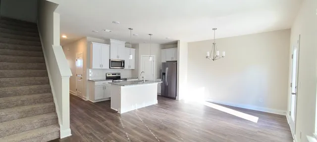 a kitchen with stainless steel appliances granite countertop a sink dishwasher a microwave oven a dining table and chairs with wooden floor