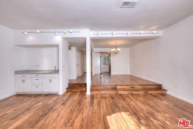 a view of an empty room with wooden floor and a chandelier