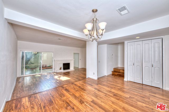 a view of empty room with wooden floor and fireplace