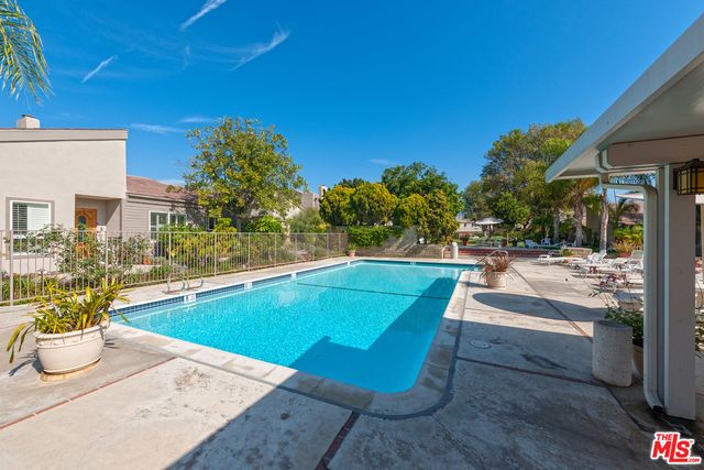 a view of a patio with table and chairs under an umbrella with a barbeque