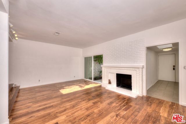 a view of empty room with wooden floor and fireplace