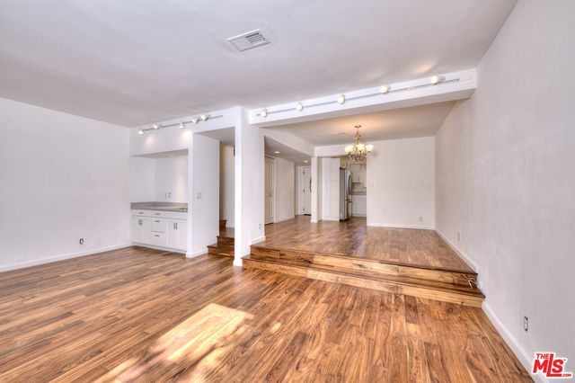 a view of a hallway with wooden floor and a bathroom