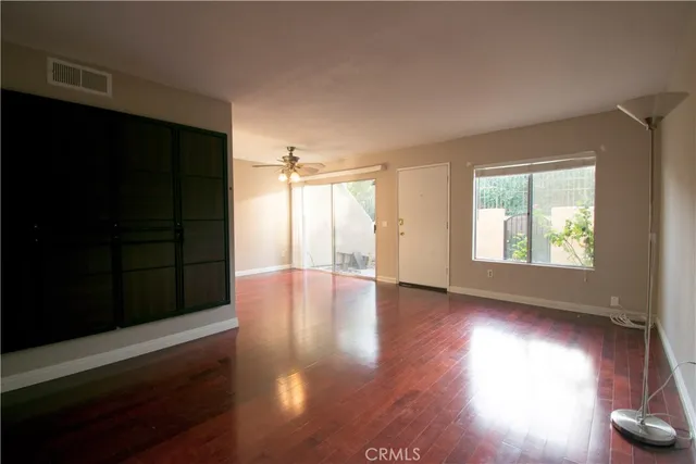 an empty room with wooden floor and windows