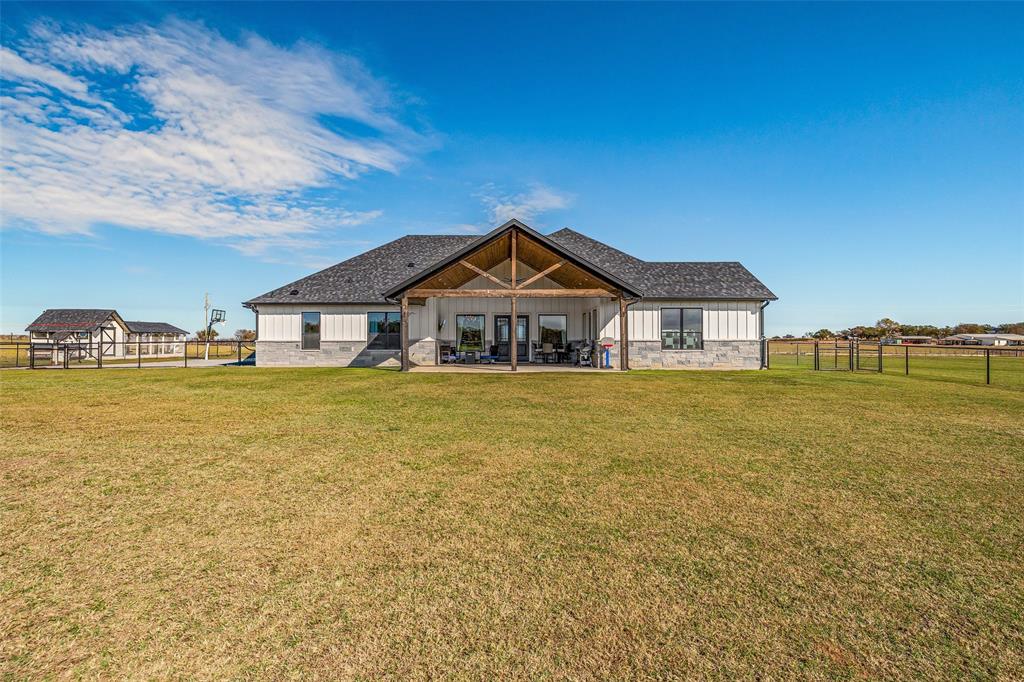 310 Runyan Rnch Road Tolar, TX 76476 - Photo 4 of 35 Rear view of property featuring board and batten siding, a fenced backyard, a patio area, and stone siding