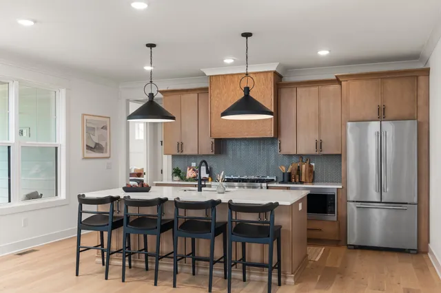 a kitchen with stainless steel appliances a dining table chairs refrigerator and cabinets
